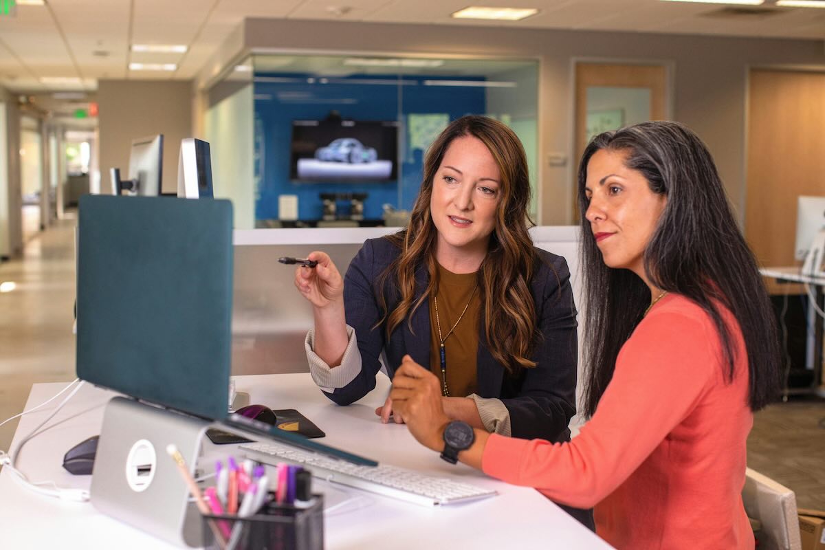 Two women looking at a computer screen discussing something